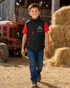 Boy walking on a farm wearing a black tractor bodywarmer with red zips and a red T-shirt