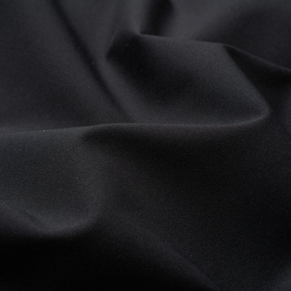 A close-up of draped black fabric with soft folds and a smooth matte texture.