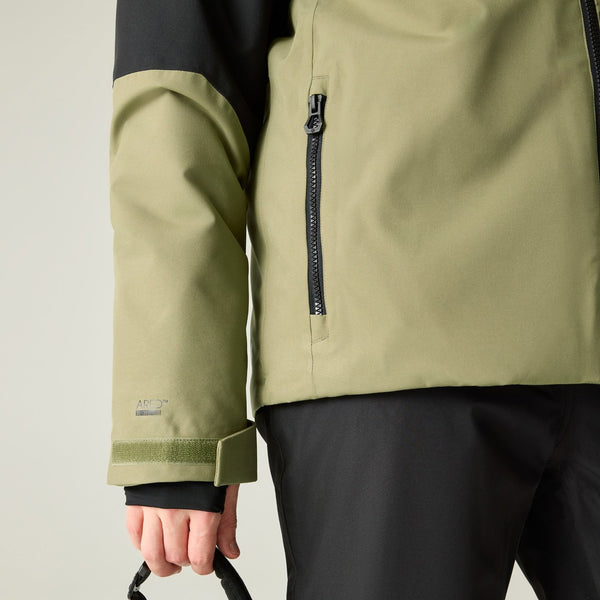 Close-up of a person wearing a technical jacket in olive green and black, showing the sleeve, chest zipper, and hand holding a strap against a light gray background.