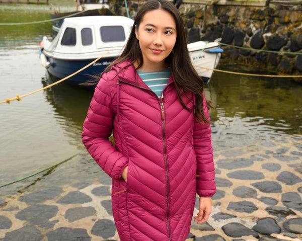 Woman wearing Lighthouse Laurel Berry coat by a harbour