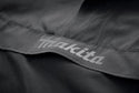 Close-up of a black jacket with 'Makita' branding on a dark background