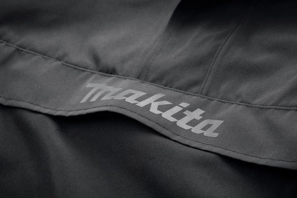 Close-up of a black jacket with 'Makita' branding on a dark background