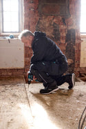 Joiner wearing Makita Onyx Stretch Trousers MK304M slim fit work trousers with holster pockets working on a floor