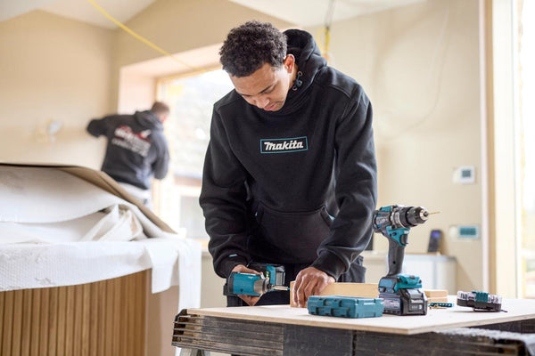Person using Makita power tools in a workshop setting wearing a Makita Origin hoodie