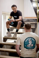 Two men sitting on a staircase with one wearing a branded t-shirt.