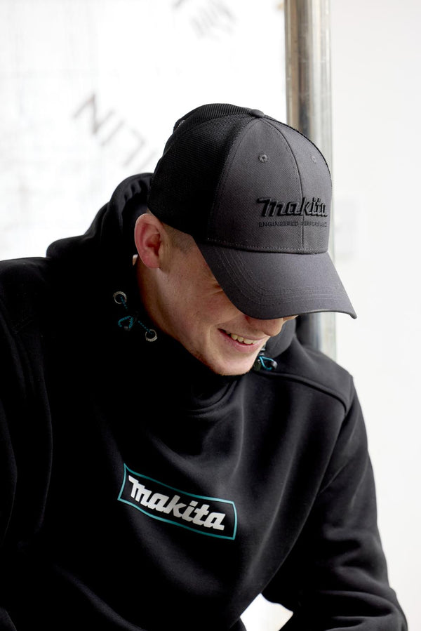 builder wearing a black Makita cap and sweatshirt in a neutral setting
