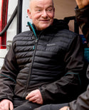 Builder wearing a black makita shield jacket with a brand logo, sitting next to a vehicle.