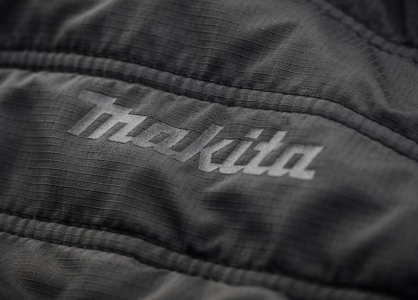 Close-up of a black jacket with 'Makila' branding.