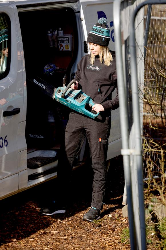 Woman holding a tool box in front of a white van wearing a Makita womens origin hoodie