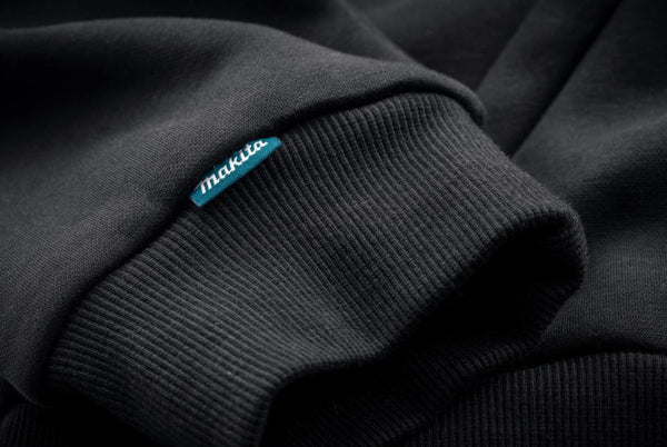 Close-up of a black sweater with a blue 'makita' label.