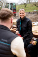 Two people sitting outdoors with a construction vehicle in the background