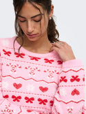 Model close-up showing pink ONLY Snowie Christmas jumper bow, heart and candy cane design
