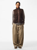 Full-length outfit showing PIECES Katty teddy gilet in Hot Fudge styled with striped top and wide leg trousers
