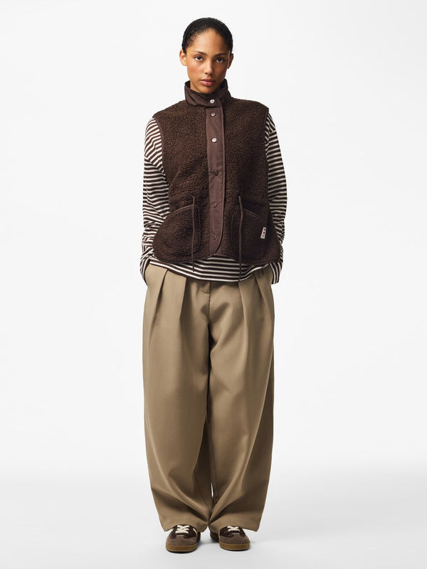 Full-length outfit showing PIECES Katty teddy gilet in Hot Fudge styled with striped top and wide leg trousers
