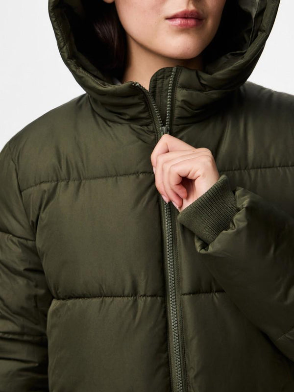 Person wearing a green puffer jacket with a hood on a light gray background