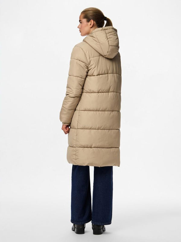 A woman shown from the back wearing a long, light beige puffer coat with a hood, paired with dark blue wide-leg jeans and black shoes, against a plain white studio background.