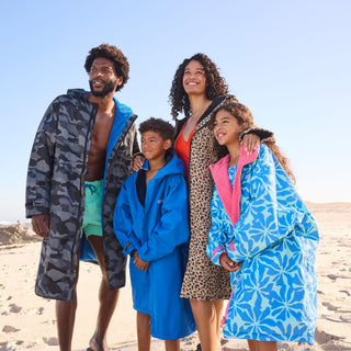 Family wearing Regatta waterproof changing robes on a beach, adults and children staying warm and dry after swimming