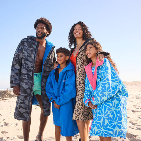 Family wearing Regatta waterproof changing robes on a beach, adults and children staying warm and dry after swimming